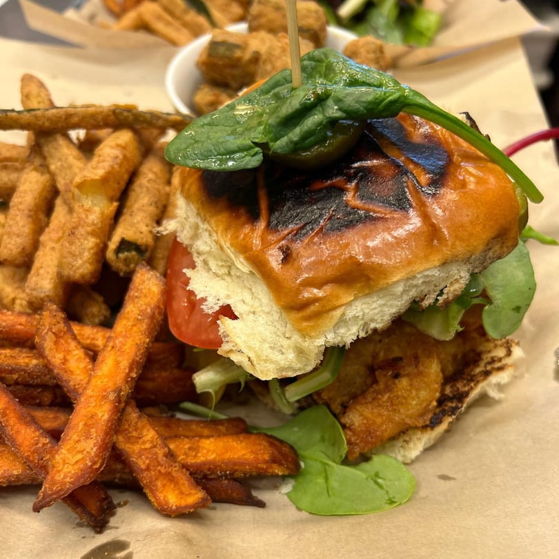A Tasha's Caribbean & Soul Food Cuisine fried chicken sandwich with sweet potato fries.