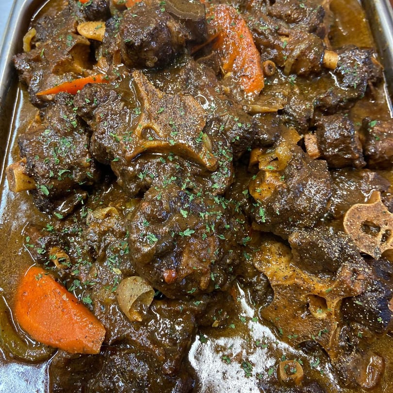 Close-up of Tasha's Caribbean & Soul Food Cuisine's oxtail stew with carrots and parsley.