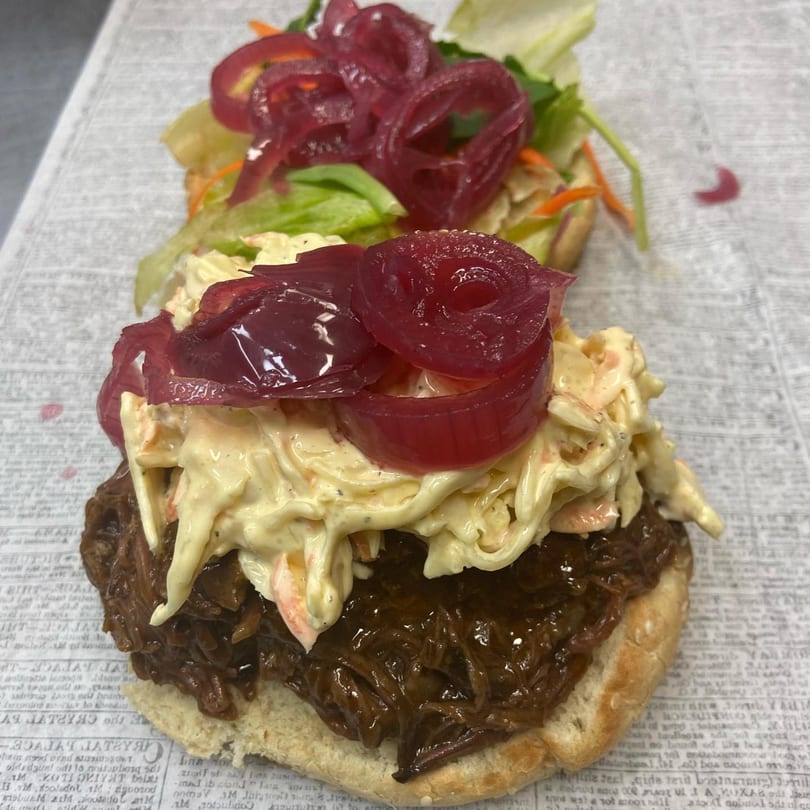 A Tasha's Caribbean & Soul Food Cuisine pulled pork sandwich with coleslaw and pickled onions.